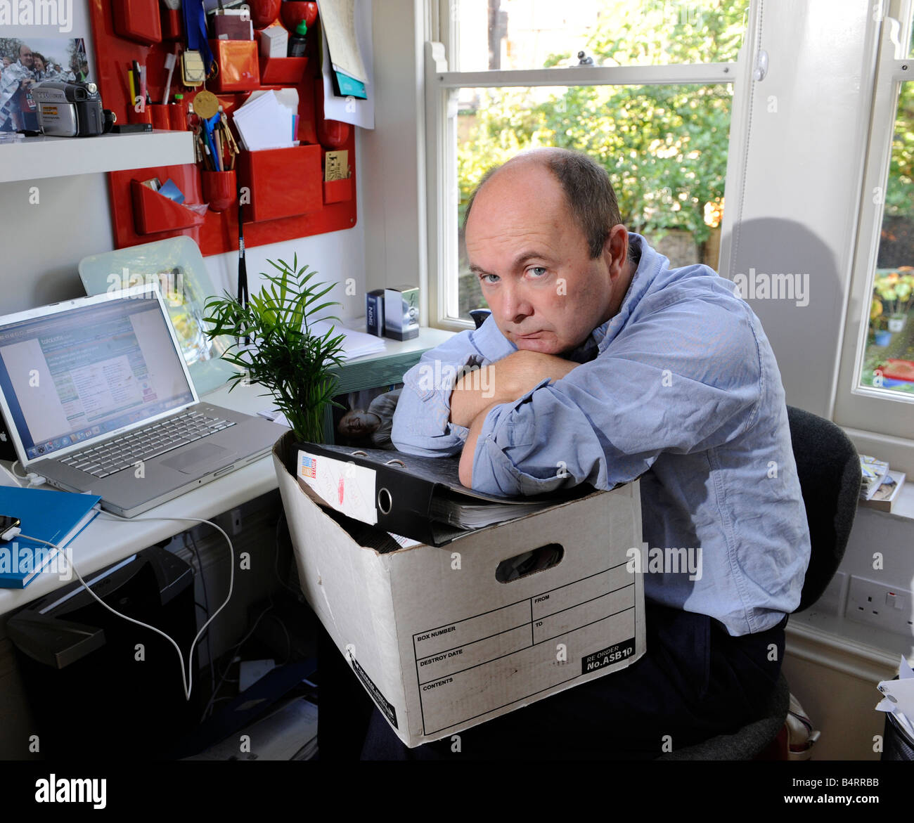 Sad and worried man packs up his desk and belongings after losing his job, being made redundant, being fired Stock Photo