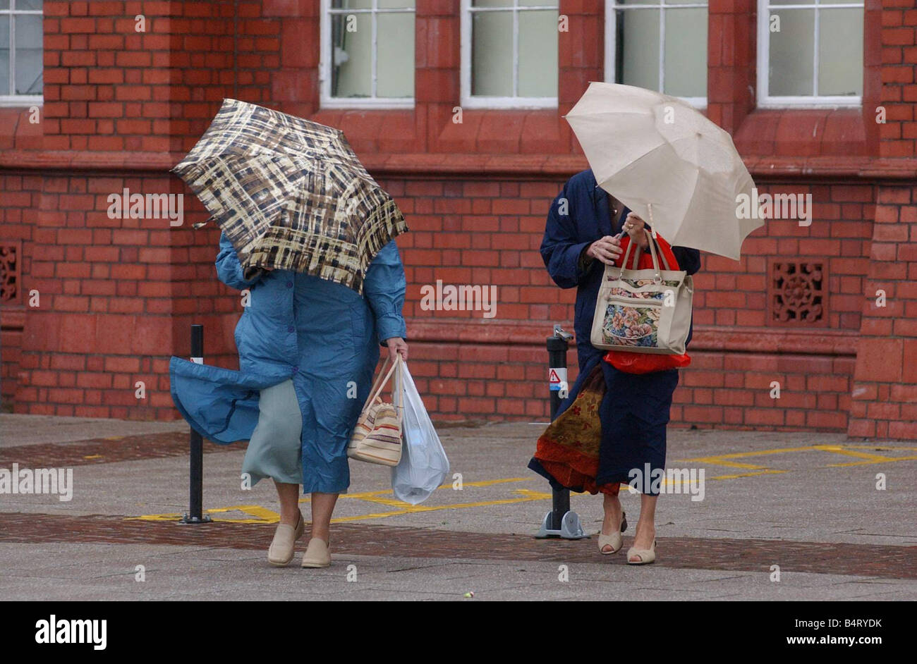 Vistors made their way around Cardiff Bay on Bank Holiday Monday to where there were fairground rides and a French food fair though they were kitted out with umbrellas due to the rain 31st May 2004 Stock Photo