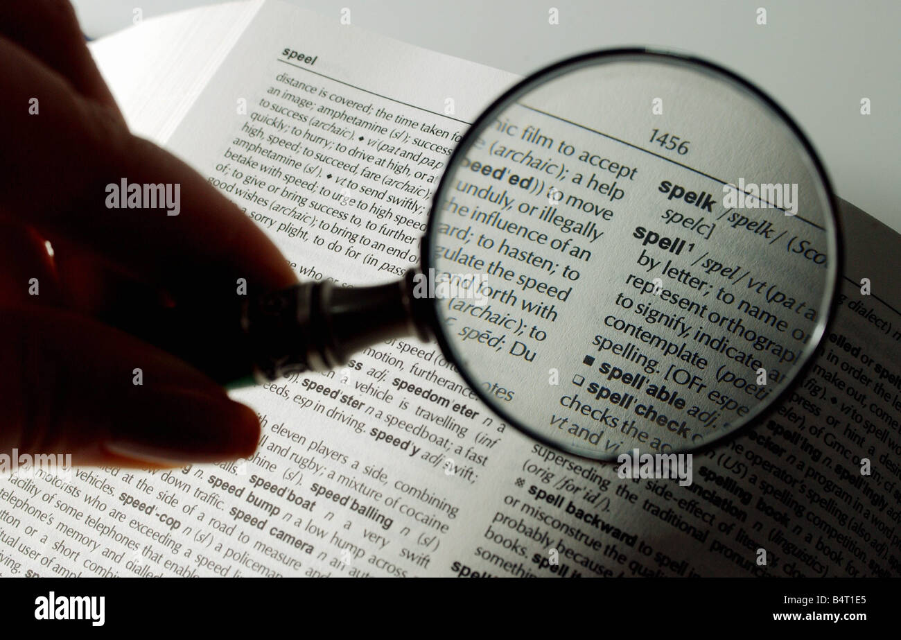 Magnifying glass held over a dictionary to highlight the word Spell
