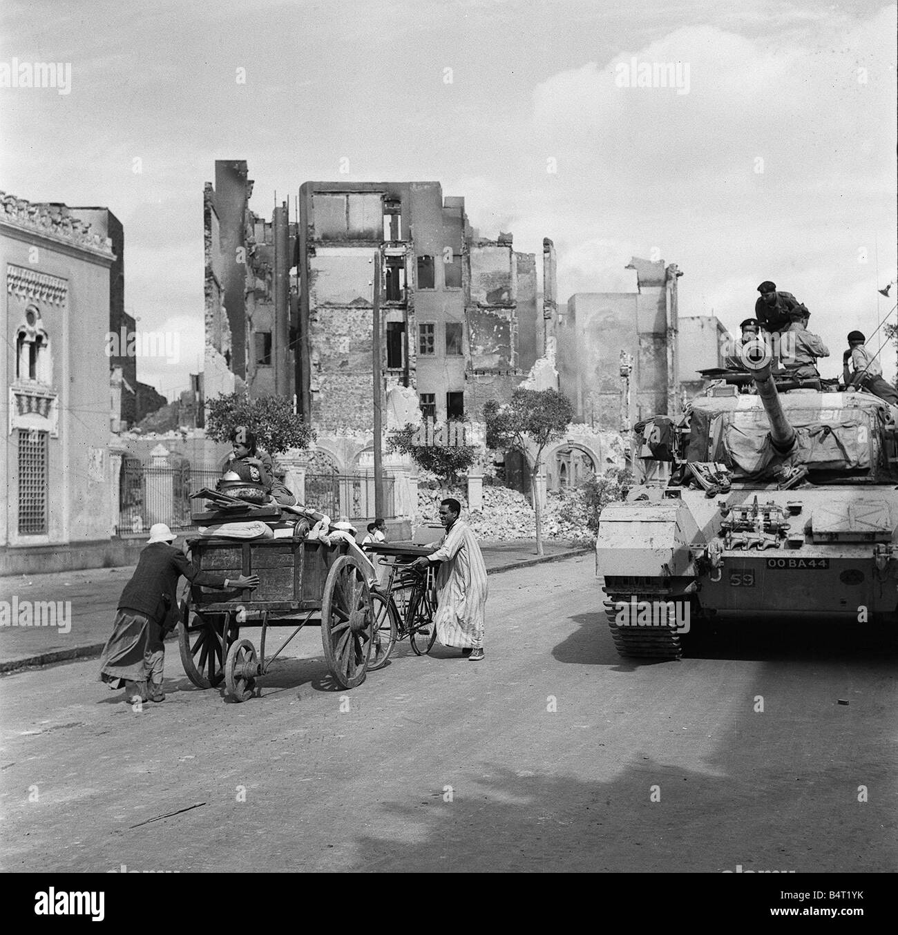 Suez Crisis 1956 Egyptian refugees remove their belongings in a cart as a Centurion tank lends support to Commando troops who are carrying out a systematic search of all the homes in Port Said for arms Stock Photo