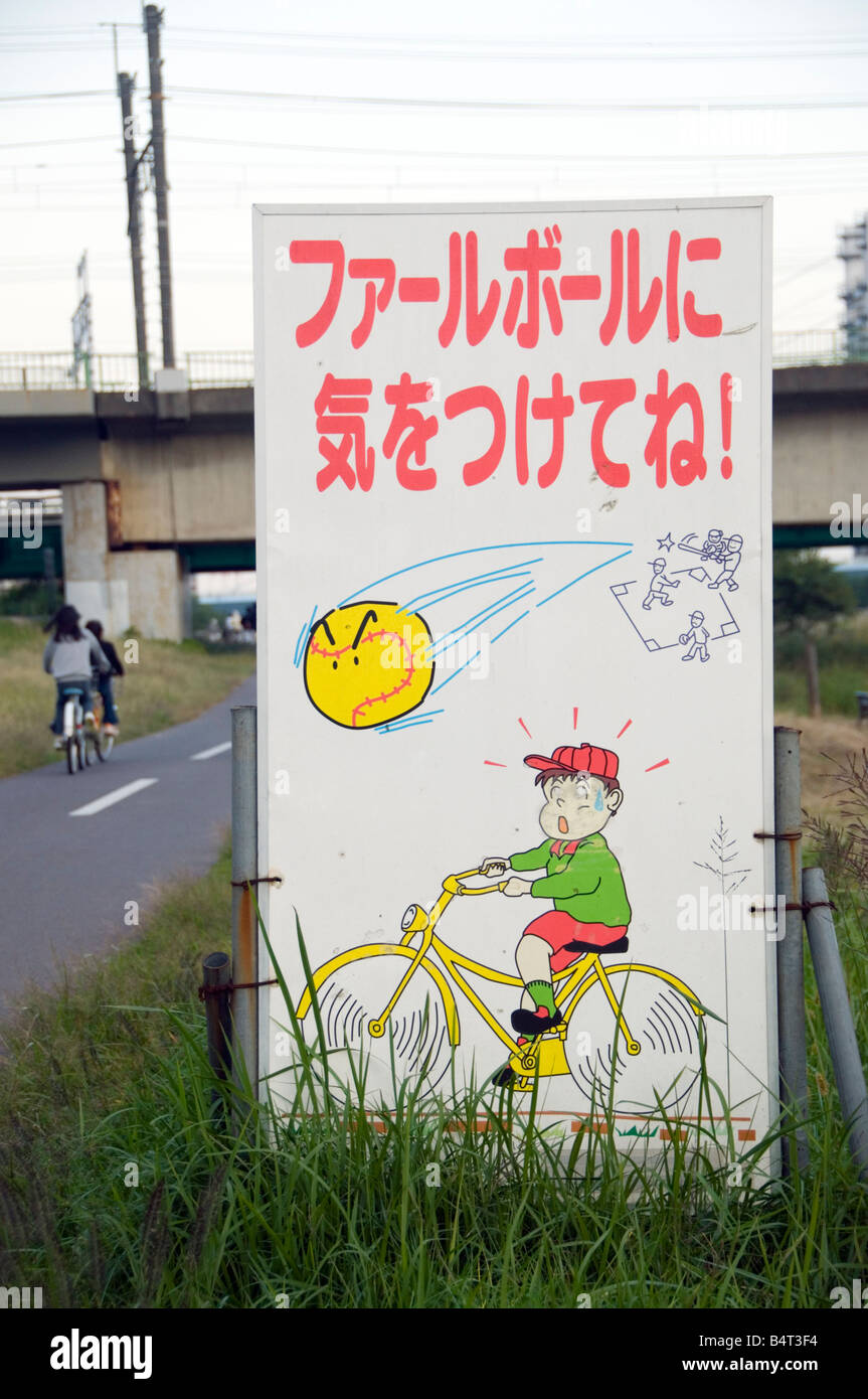 Sign urging caution while cycling past a ball diamond Tokyo Japan Stock