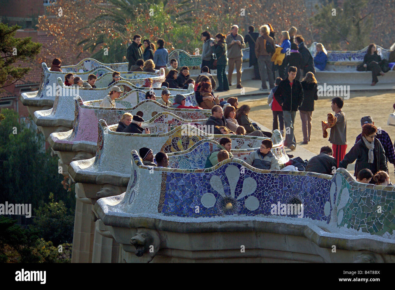 People enjoying the sunshine at Park Guell in Barcleona and showing the mosaic work on the seating area of the main terrace. Stock Photo