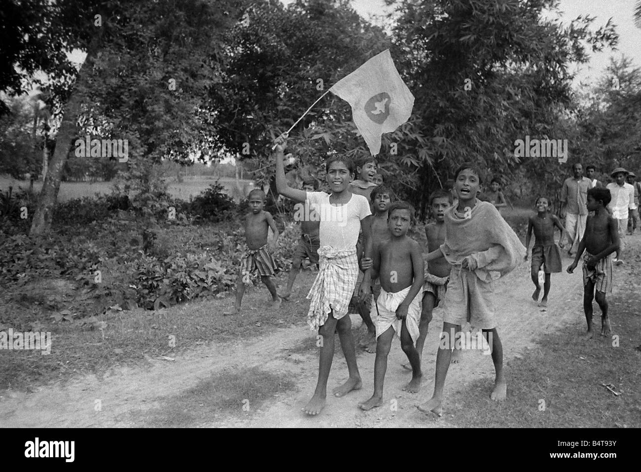 A large area of East Pakistan territory is under the control of the Bangladesh Freedom Fighters. These pictures were taken on patrol with an operational unit whose camp is in the Jungle just inside the Indian border.;Our Picture Shows: A group of children from one of the villages along the East Pakistan - Indian border greet the Bangladesh Freedom Fighters patrol. The children are waving the flag of the BFF Stock Photo