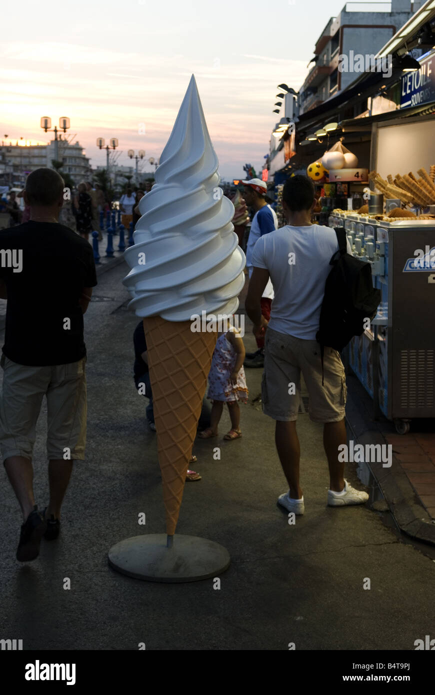 a large ice cream model stands in front of ice cream parlour with customers nearby Stock Photo