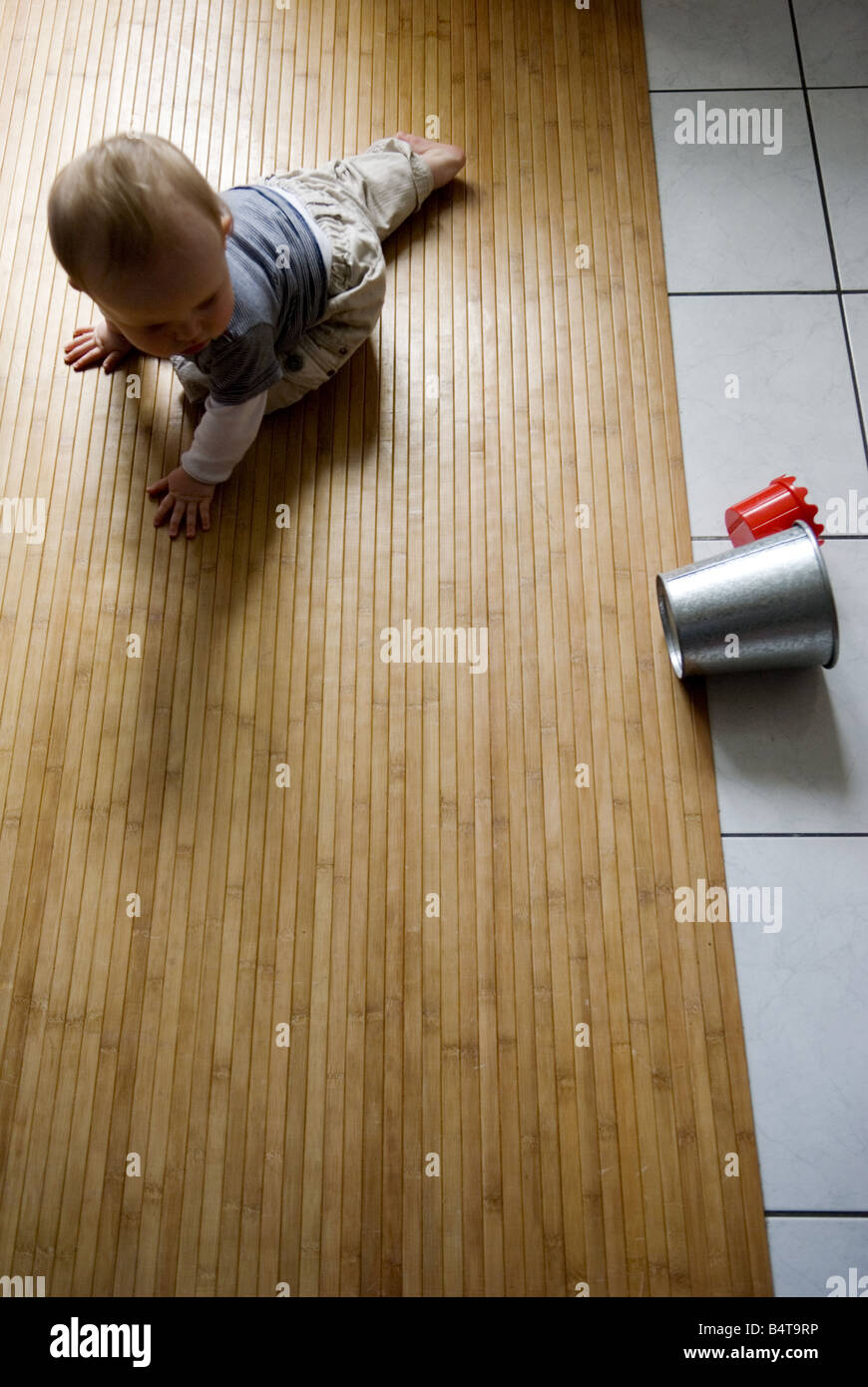 Aerial View Of Baby Crawling Alone On Wooden Kitchen Floor Looking