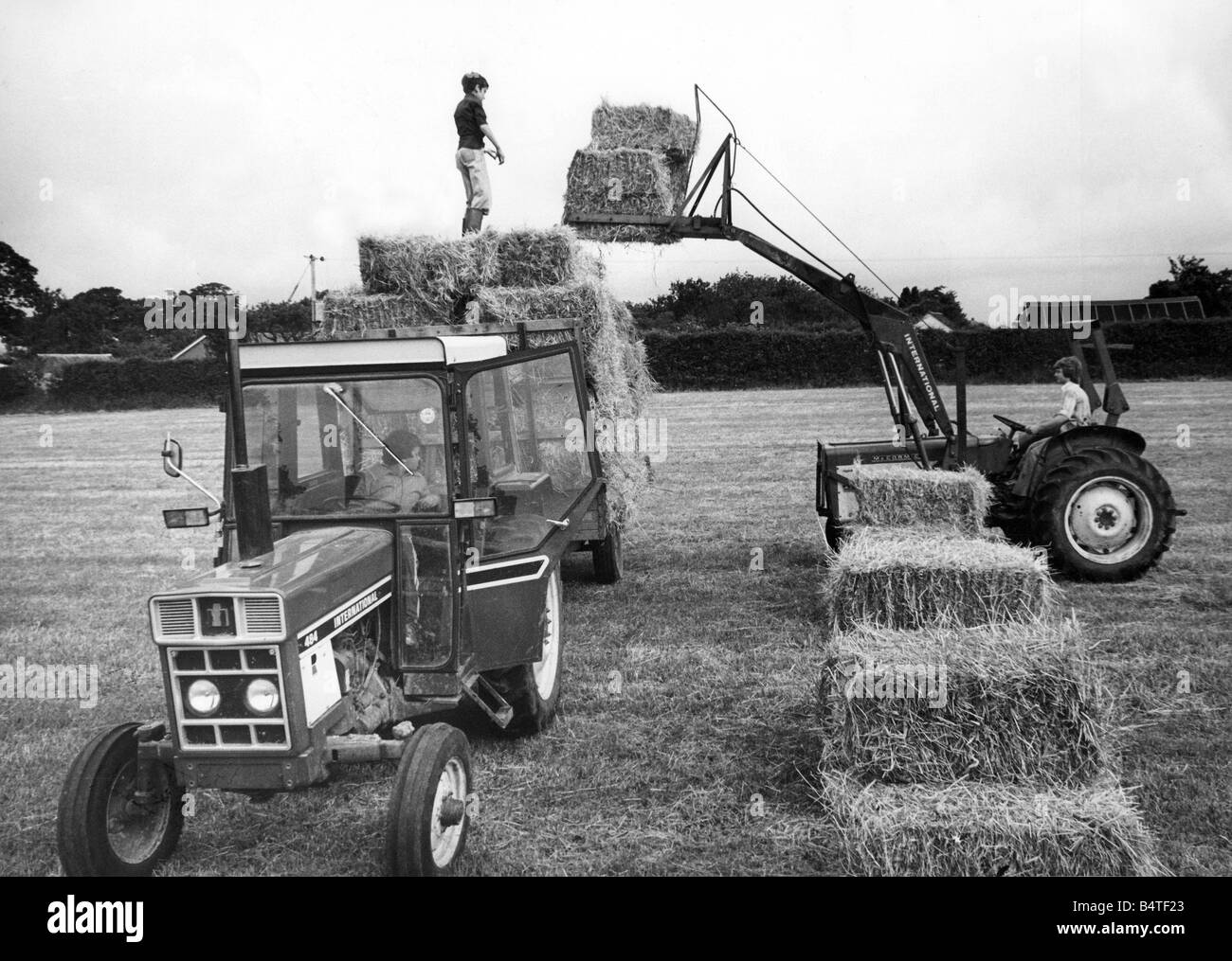 Farm hands at Blackwell Farm near Carlisle lifting bales from the hayfield Stock Photo