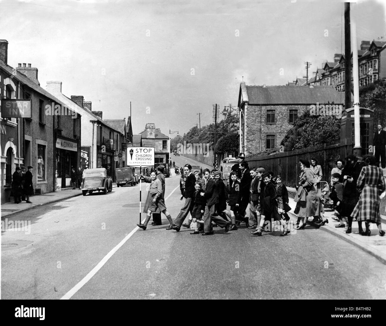 Road Safety Lollipop Man Woman A new road crossing for children at Aberavon Pictured are children being directed across the road at Port Talbot s main Cardiff to Swansea road 17th May 1952 Stock Photo