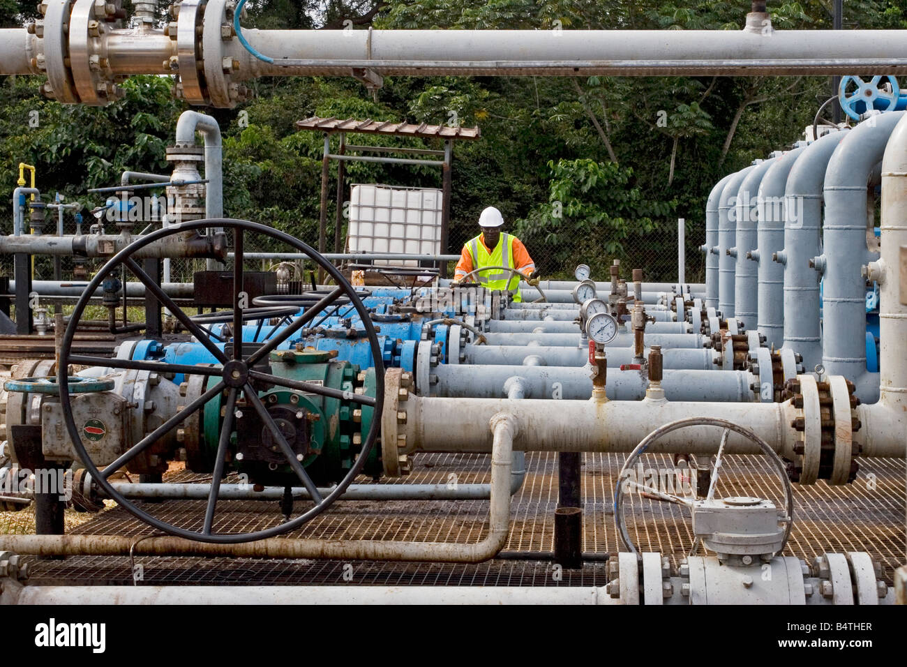 Onshore oil and gas processing plant showing pipework with oil production worker doing