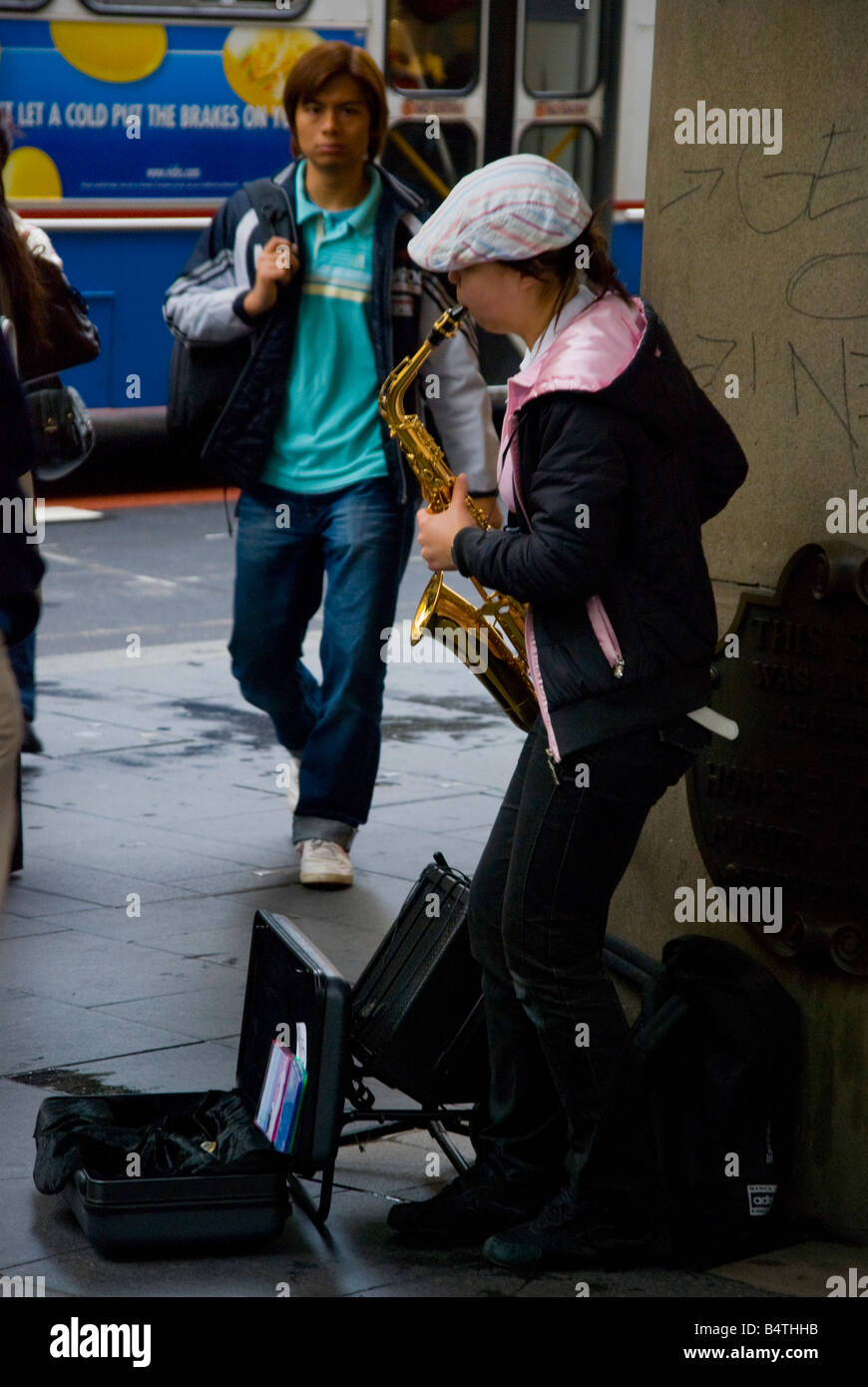 A busking female saxophone player in inner city CBD Sydney Australia Stock Photo