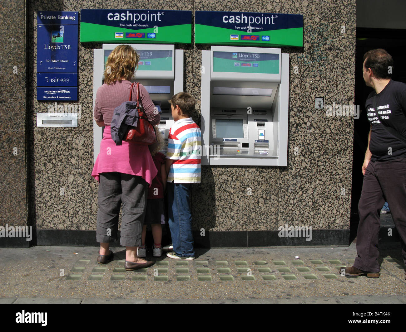 Mother and son withdrawing money at cashpoint in London Stock Photo