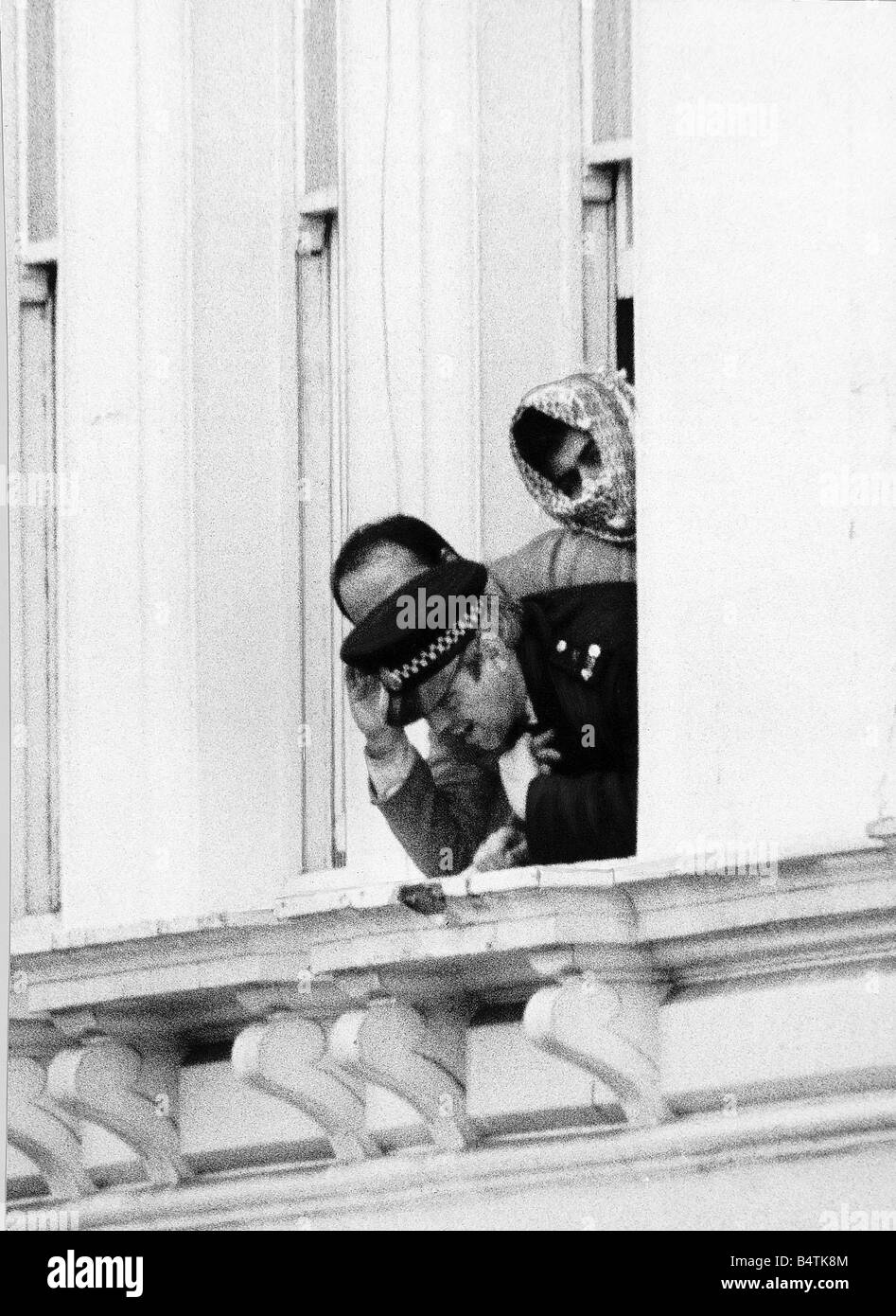 A police officer leaning out of the e window of the Iranian Embassy with two terrorists masked during the the fifth day of the Iranian Embassy siege as negotiations continued May 1980 Stock Photo
