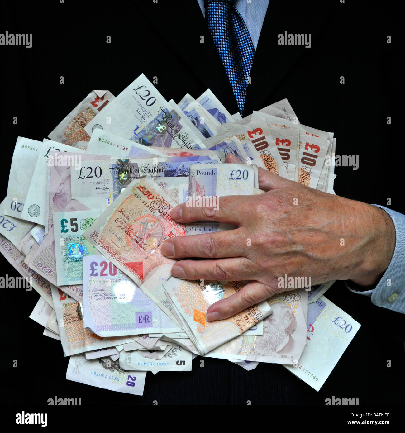 Man in dark office business suit hand on close up stack of money bank notes uk cash currency concept for bankers fat cats greed Men in Suits Lifestyle Stock Photo