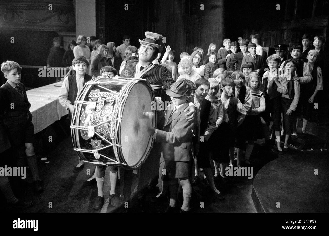 Lionel Bart who wrote Oliver plays the big drum from the Irish Guards as he marches round the Stage with the orphans and cast of Oliver There was a party on the stage of the New Theatre St Martins Lane London when the children in the show met some orphans from children homes Dr Barnardos Home Ilford Enfield Kingston and Twickenham The party was to mark the longest ever running musical in the West End 2292 shows Stock Photo