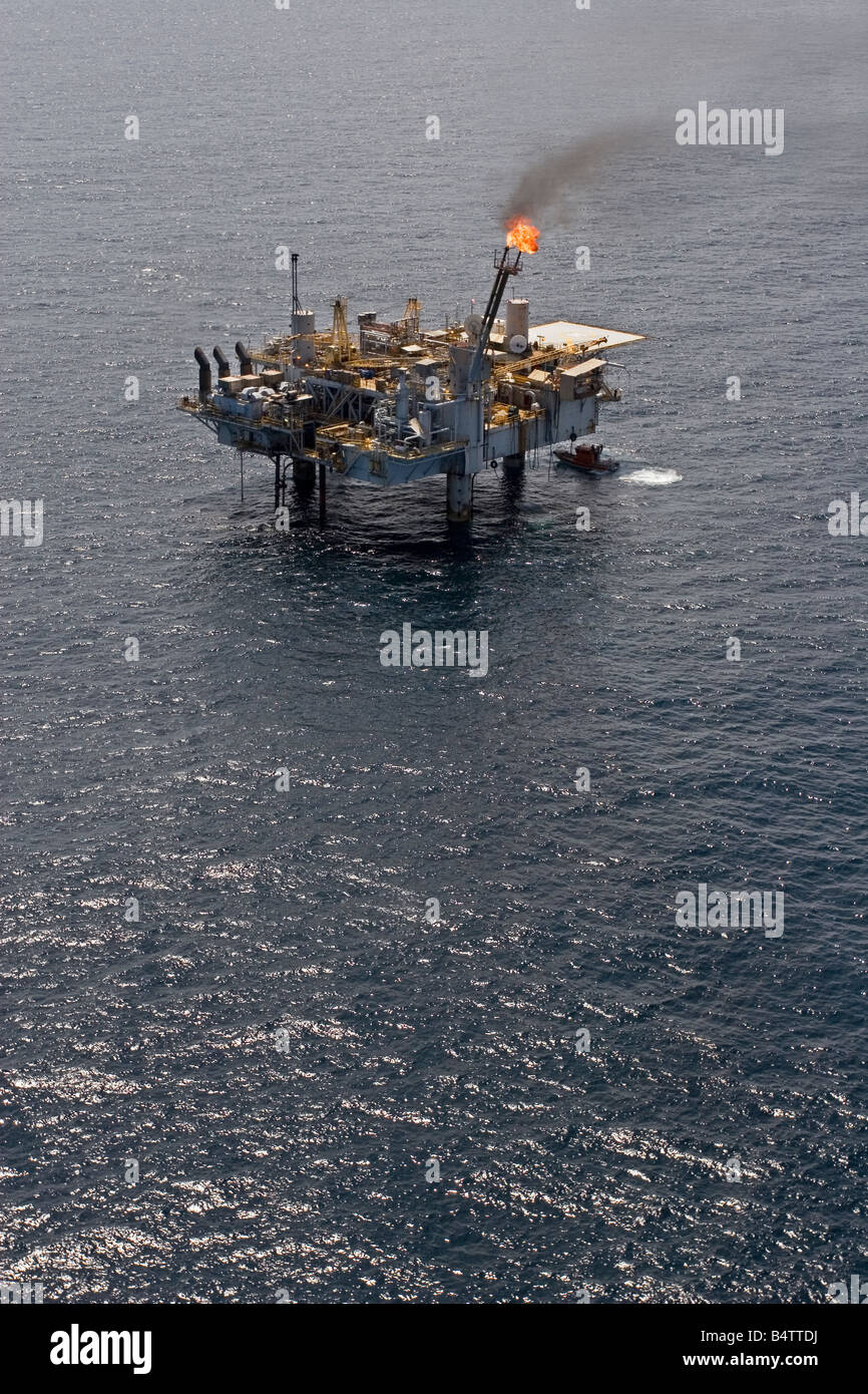 Aerial of offshore oil and gas production marine rig with safety boat as well as helicopter deck and safety flare, Gabon Stock Photo