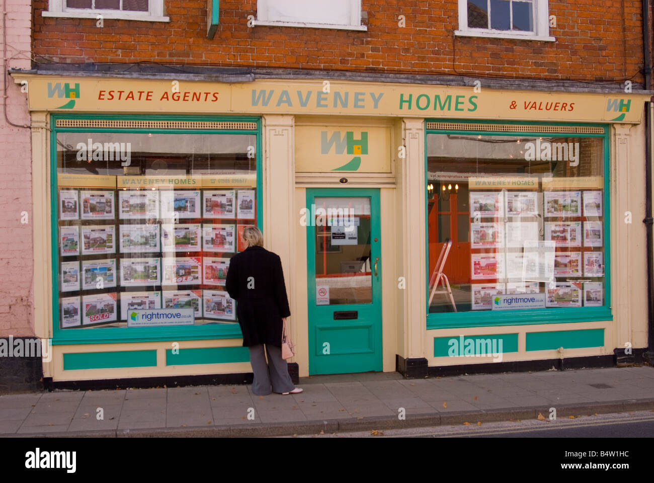 Young woman looking in window of Waveney Homes Estate Agents for houses