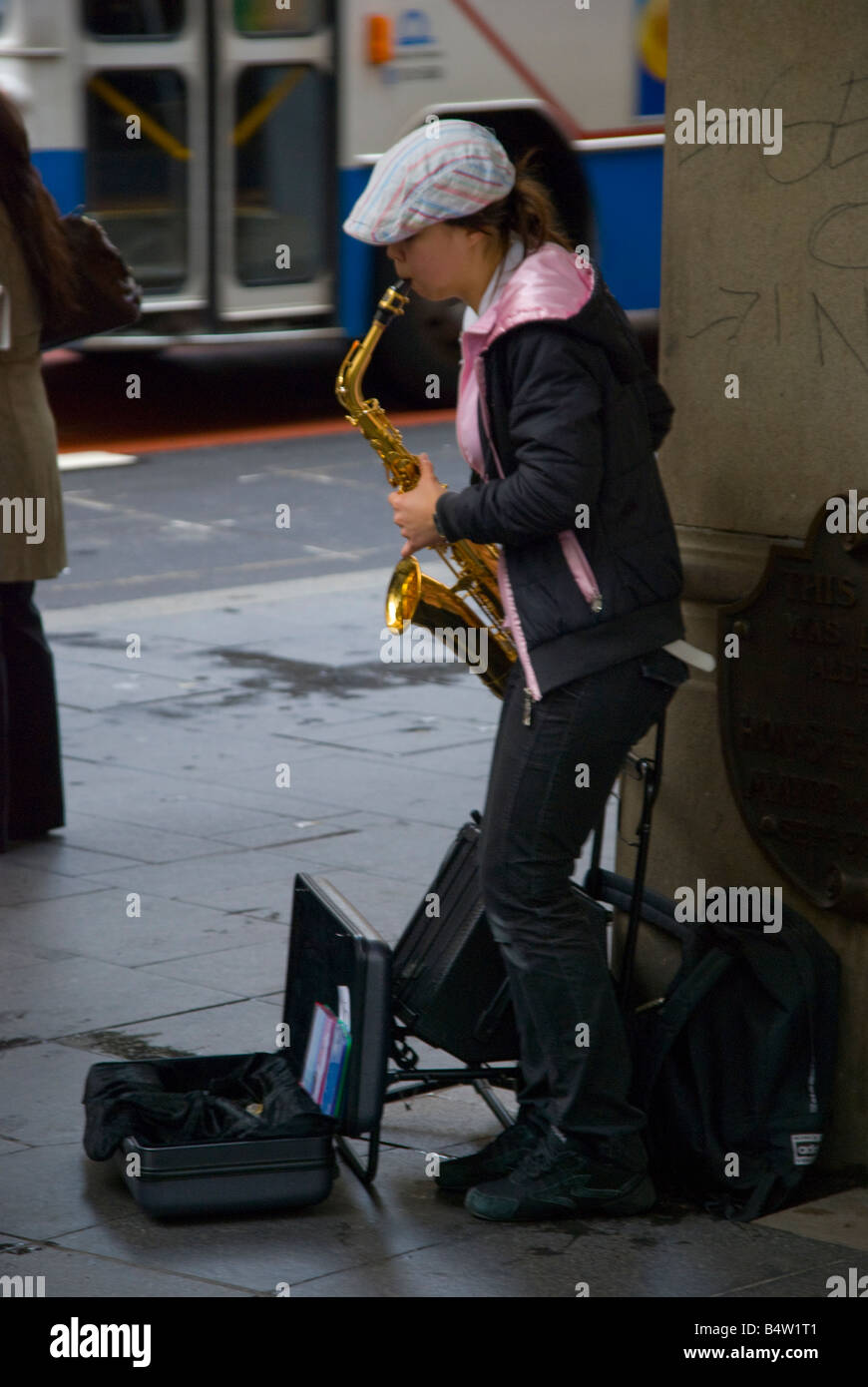 A busking female saxophone player in inner city CBD Sydney Australia Stock Photo