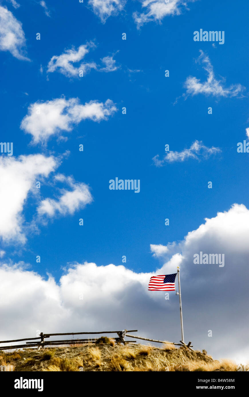 American flag on top of the hill. Blue sky and white clouds above. Stock Photo