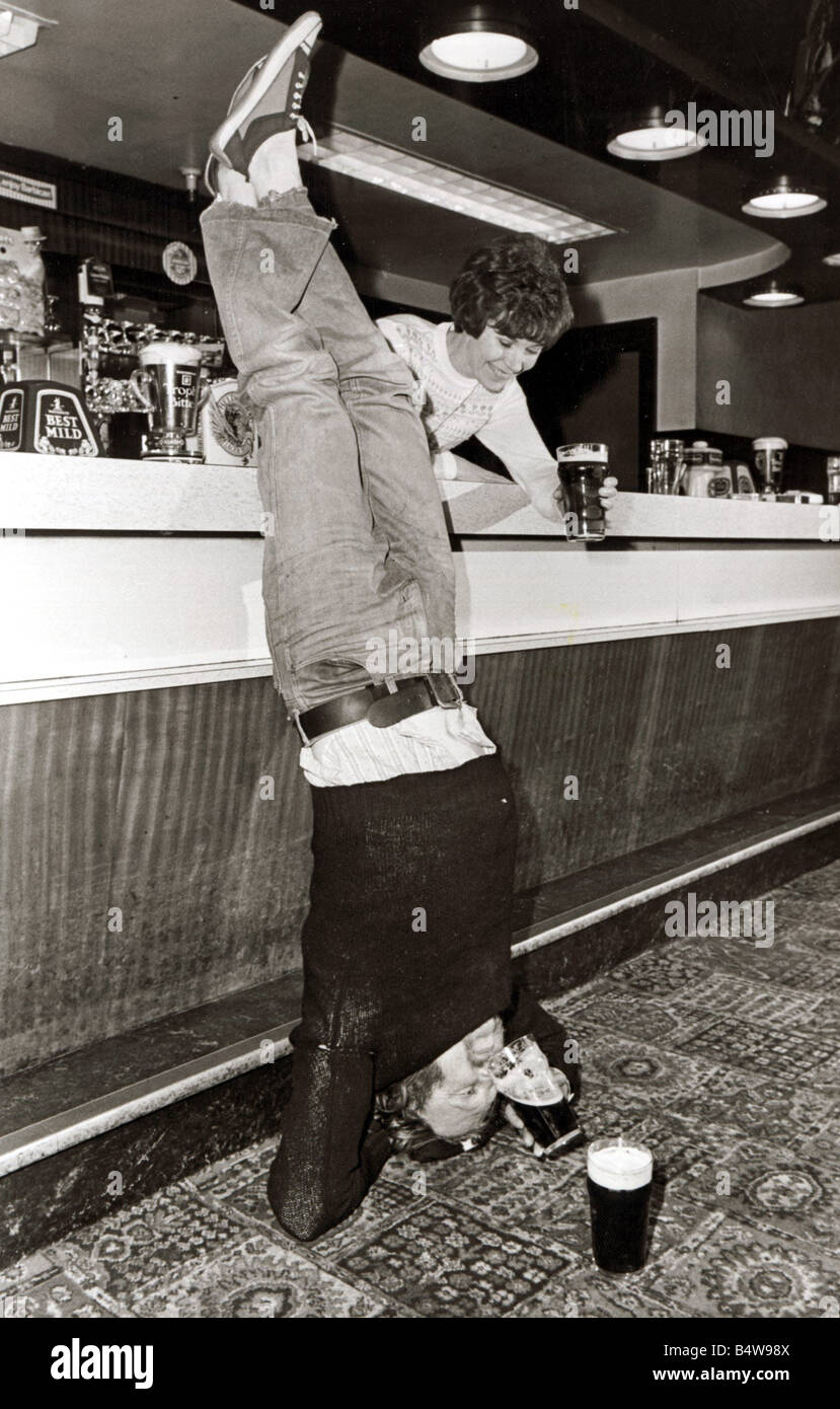 Drinking A man doing a headstand in his local pub drinking his pint of beer upside down 1980s Stock Photo