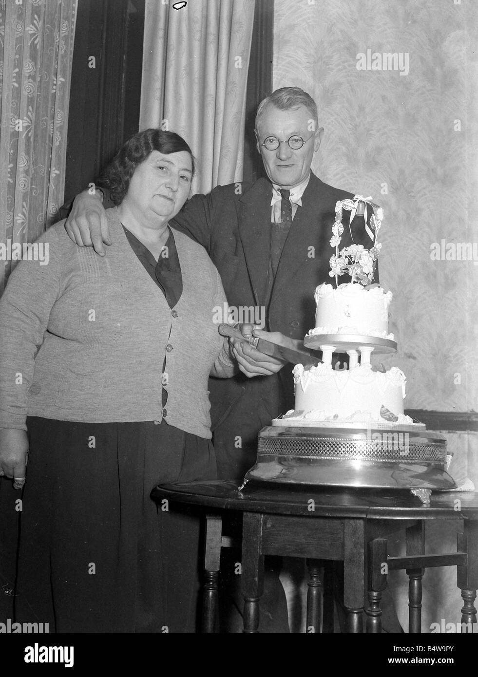 The happy couple cut the wedding cake at the reception 1949 Stock Photo