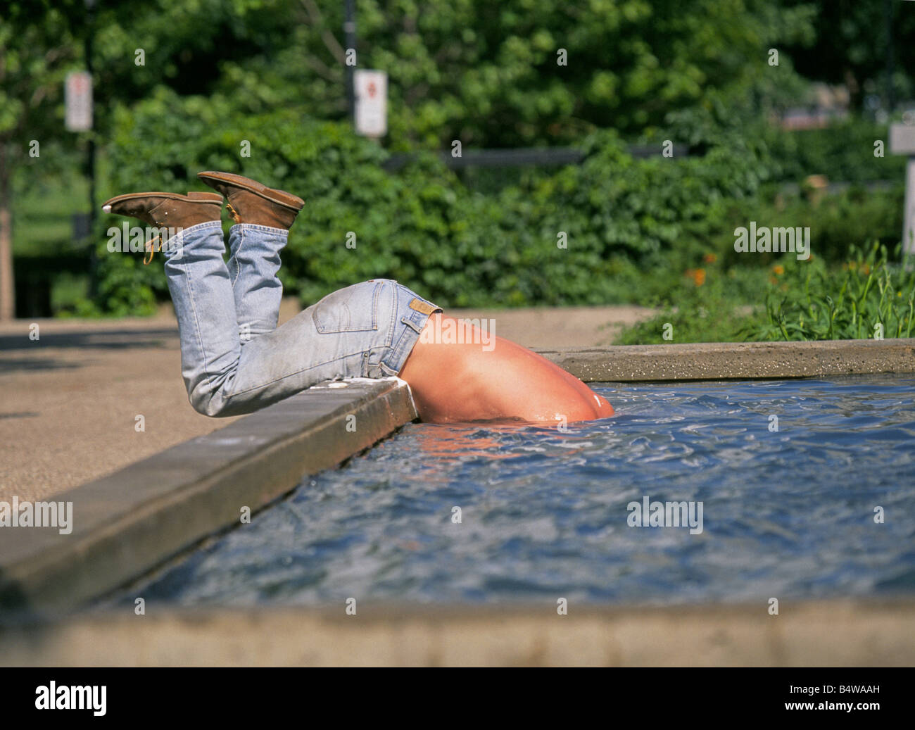 A homeless person taking a bath and washing his hair in a fountain in