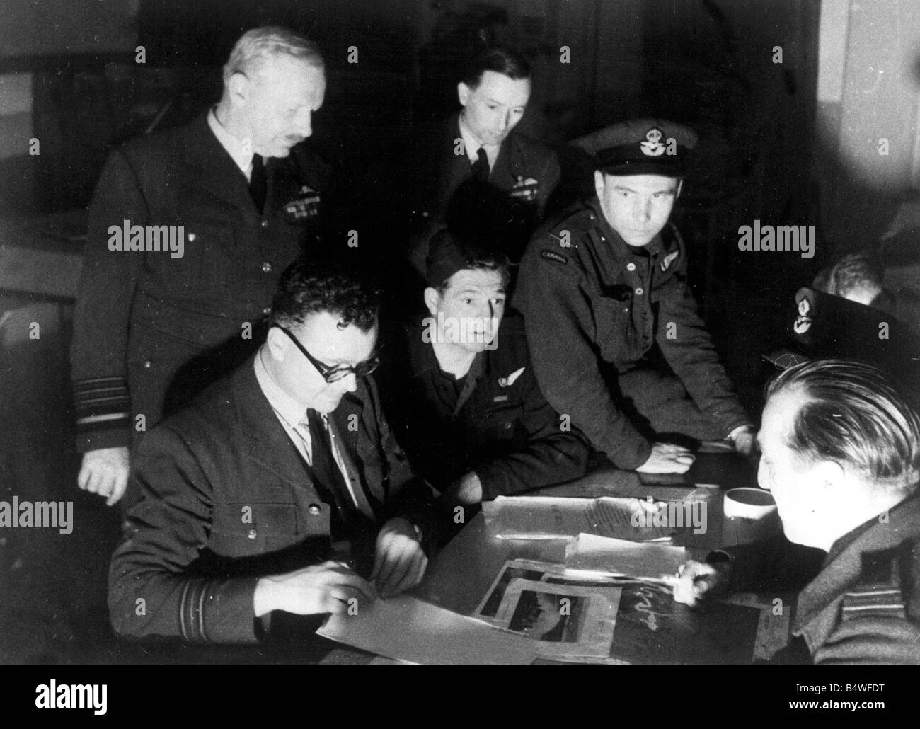 Air Officer Commander in Chief Arthur Bomber Harris standing nearest camera and Air Vice Marshal R A Cochrane listen to the interrogation of one of the crews during the RAF bombing raids on the German dams Mohne and Eder in World War Two Circa 1943 Stock Photo