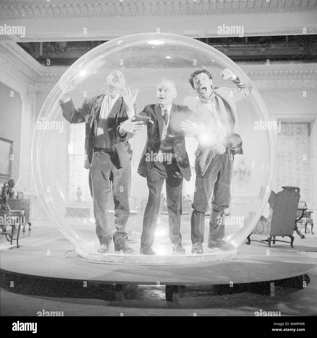 Left to right Lionel Jeffries Eric Portman and Laurence Harvey seen here on the set of The spy with a cold nose at Shepperton Studios The actors are seen here in The dome an anti bugging device constructed of perspex and 9 foot in diameter In the film the three actors get locked inside the device July 1966 W7237 Stock Photo