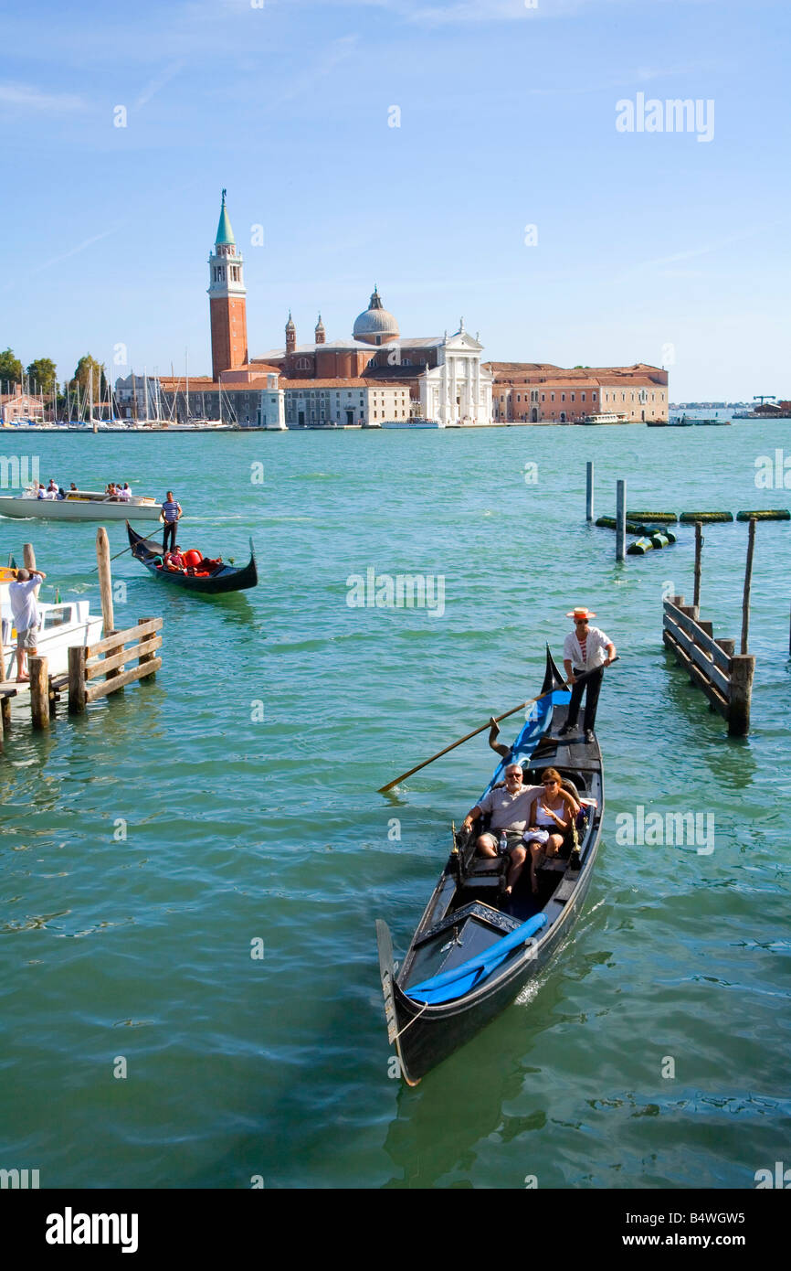Couple take a Gondola Ride with the Basilica San Giorgio Maggiore across the Lagoon in the background Stock Photo