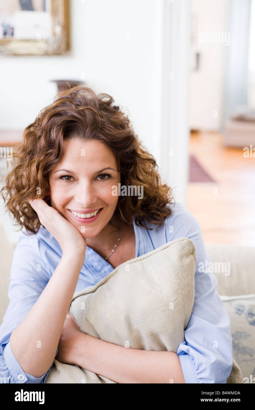 Woman hugging pillow sitting on a couch Stock Photo Alamy