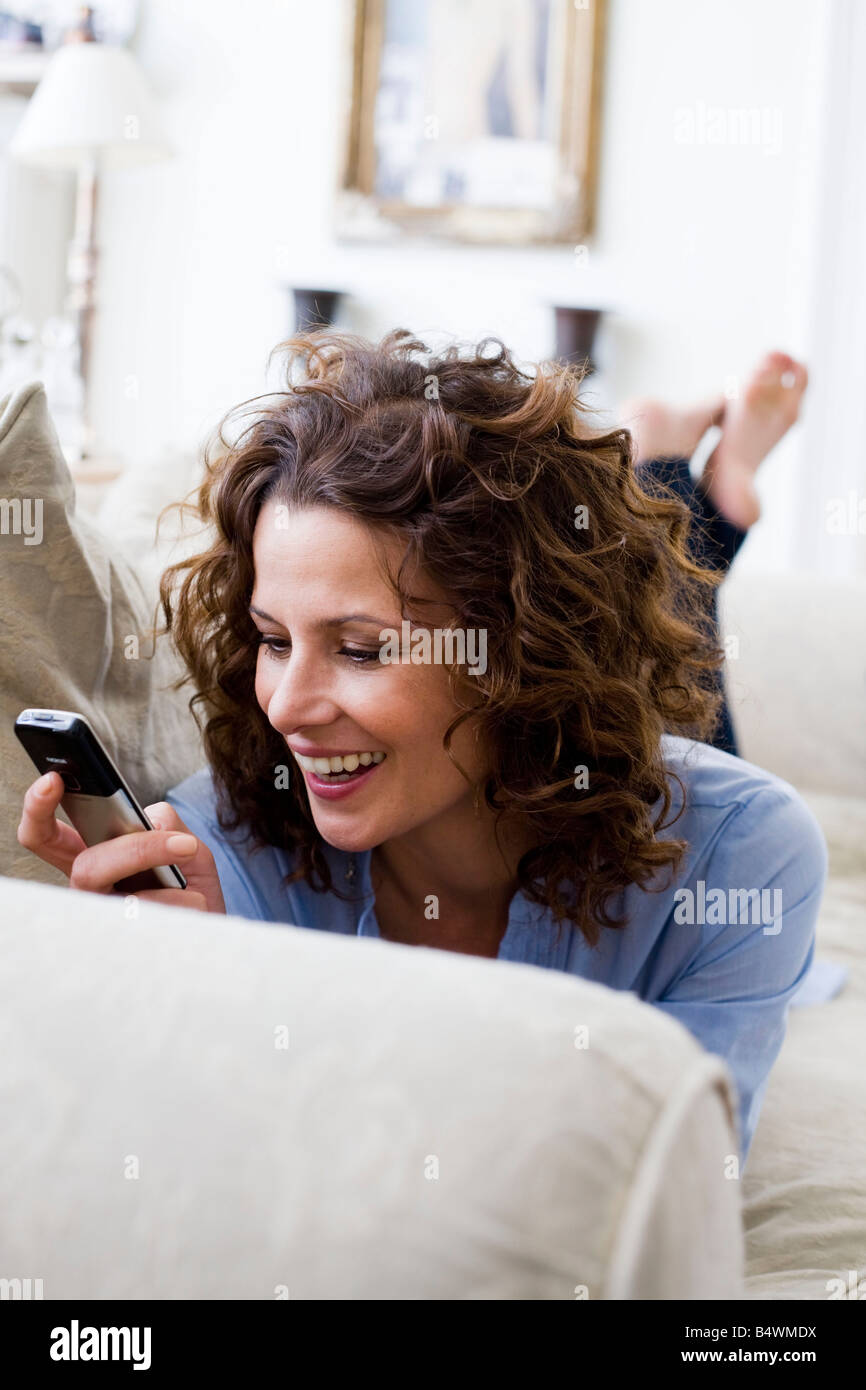 Woman texting on her handy, laying Stock Photo