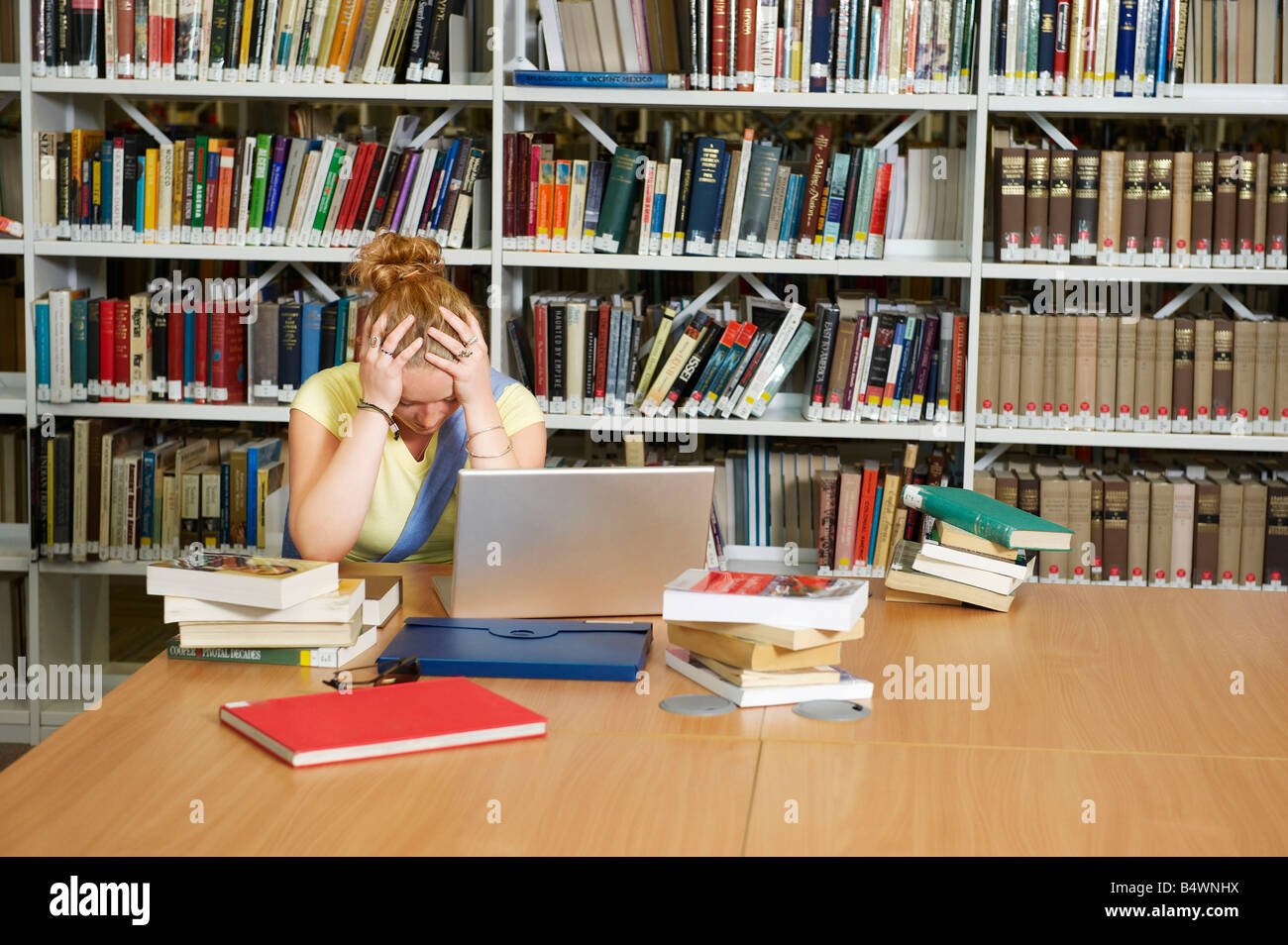 Despairing young woman in library Stock Photo
