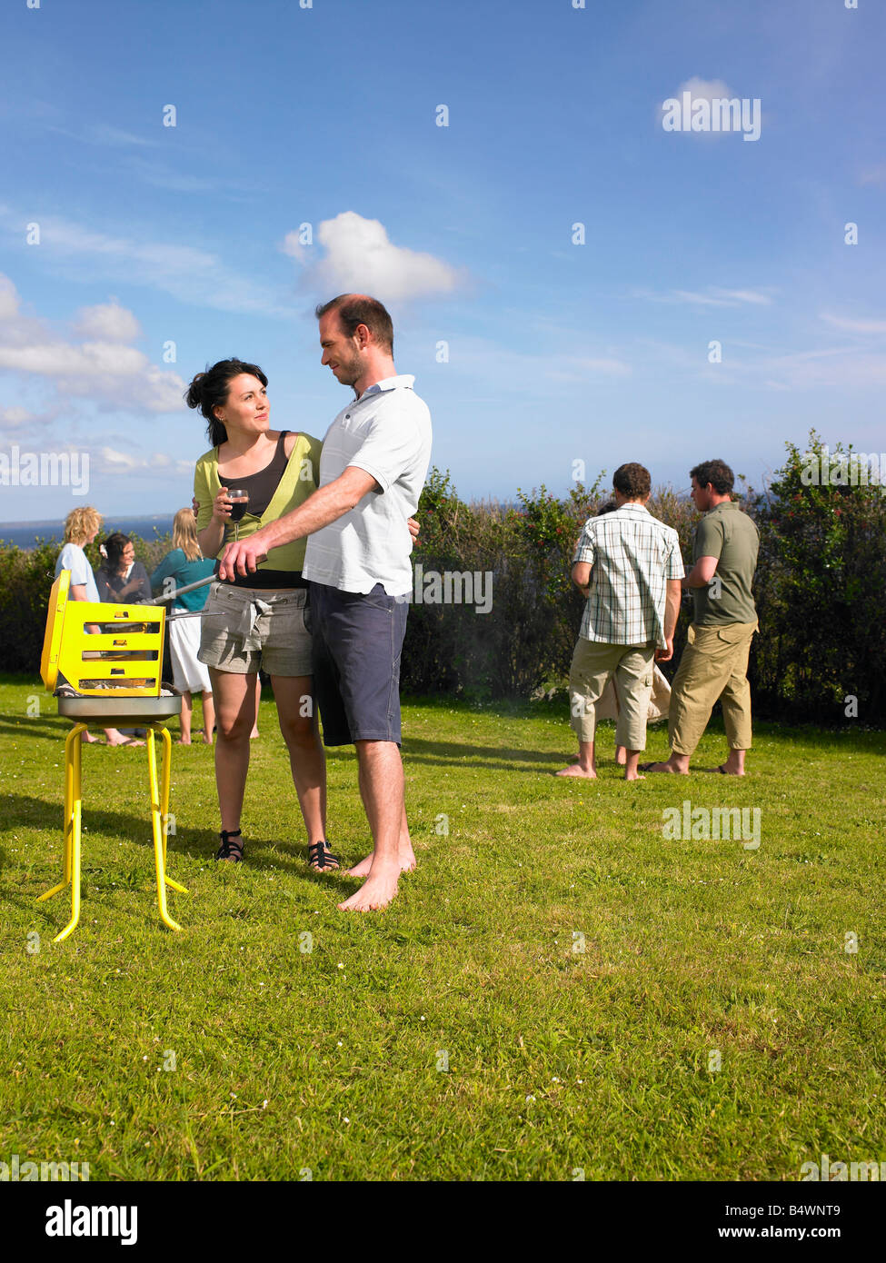 Man tending barbecue with woman Stock Photo