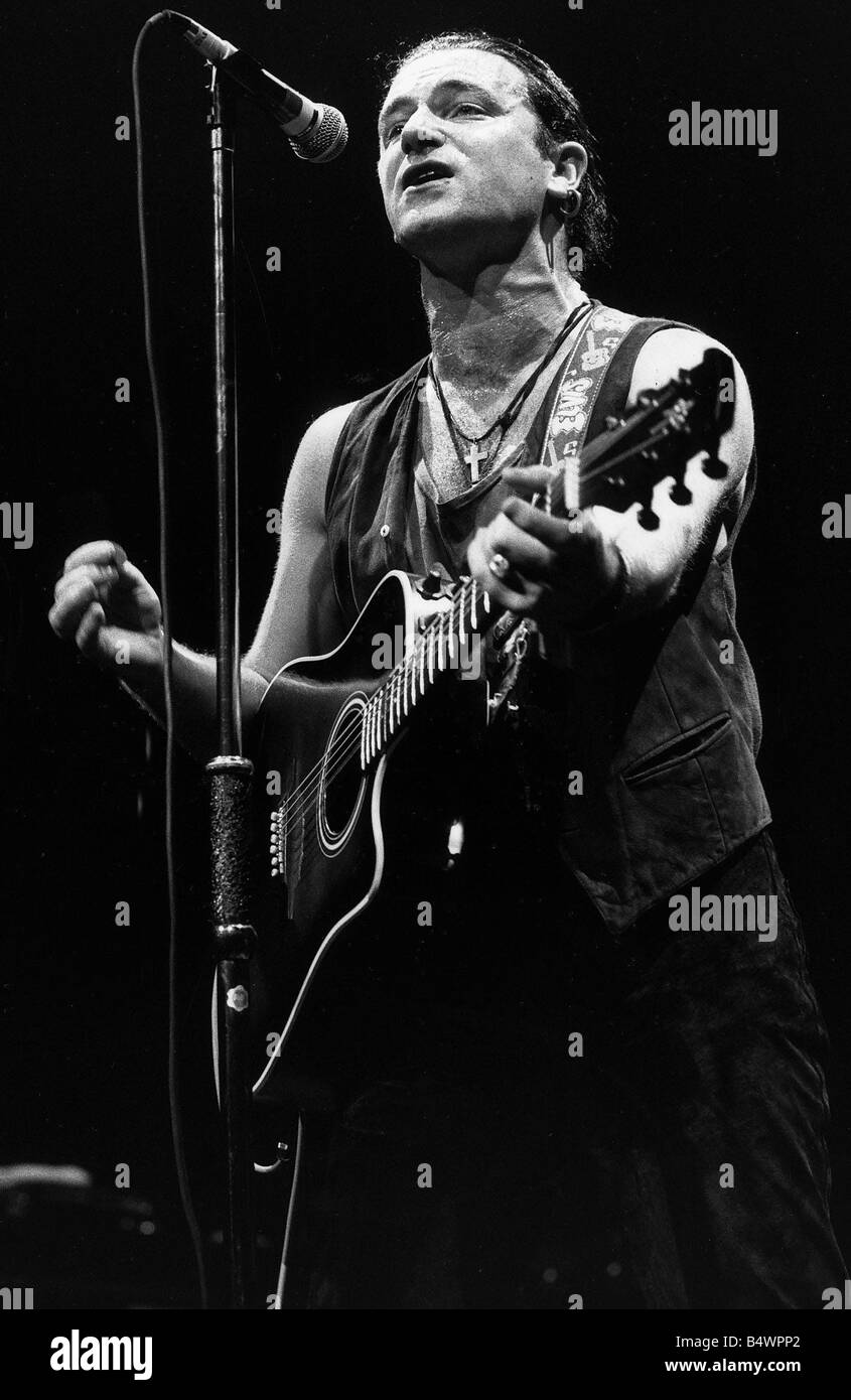 U2 Irish pop singer Bono playing guitar and singing at Wembley Arena in 1987 Stock Photo