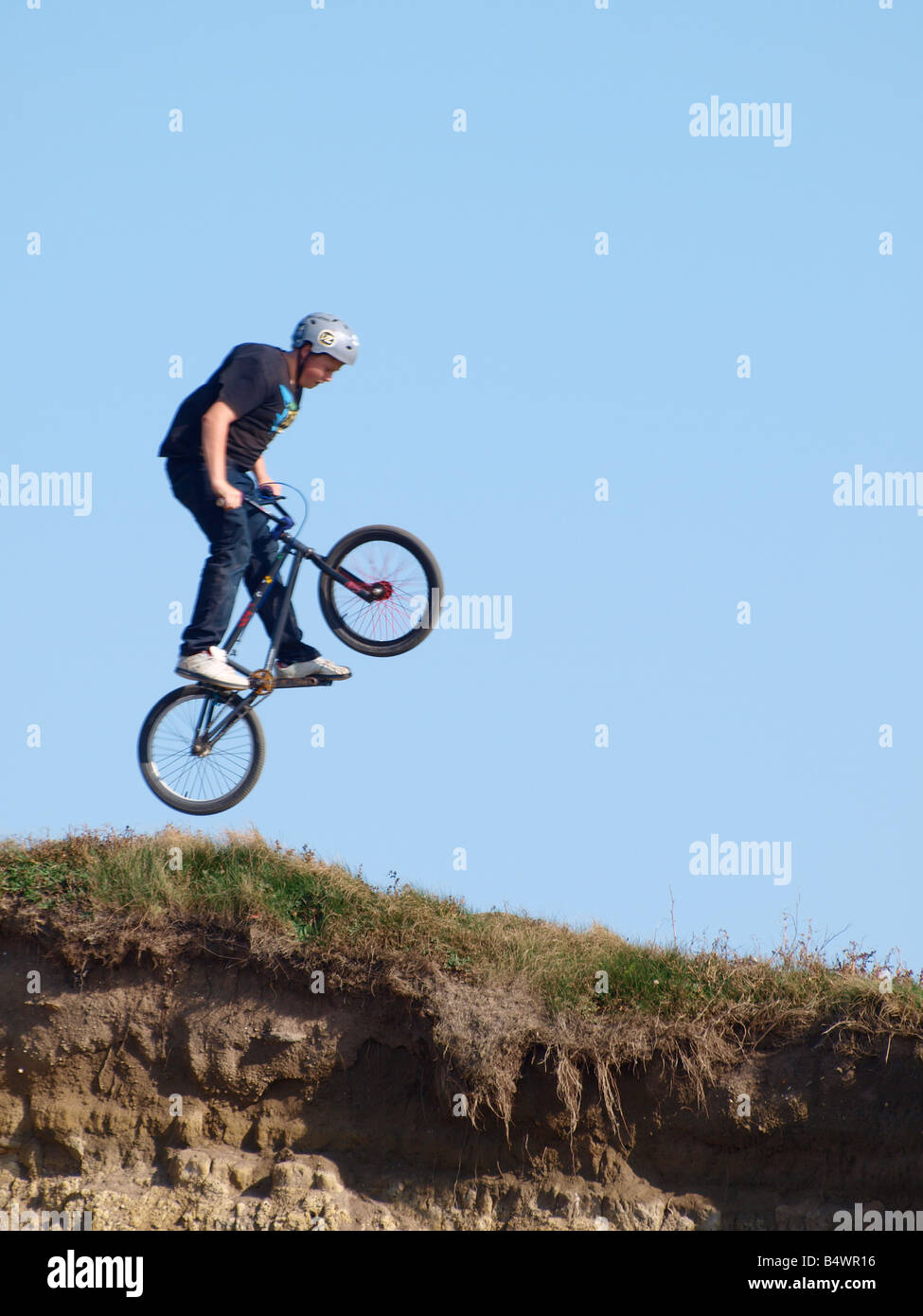 Boy wearing safety helmet jumping on a bmx bike Stock Photo Alamy