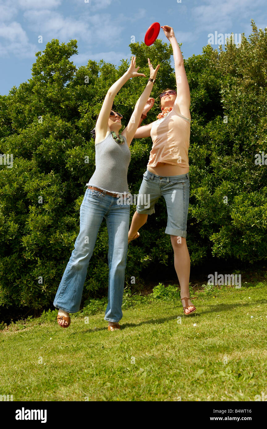 Two women jumping to catch a frisbee Stock Photo