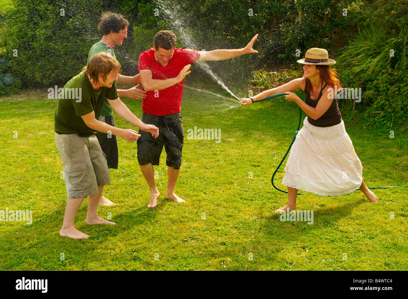 Woman spraying men with garden hose Stock Photo Alamy
