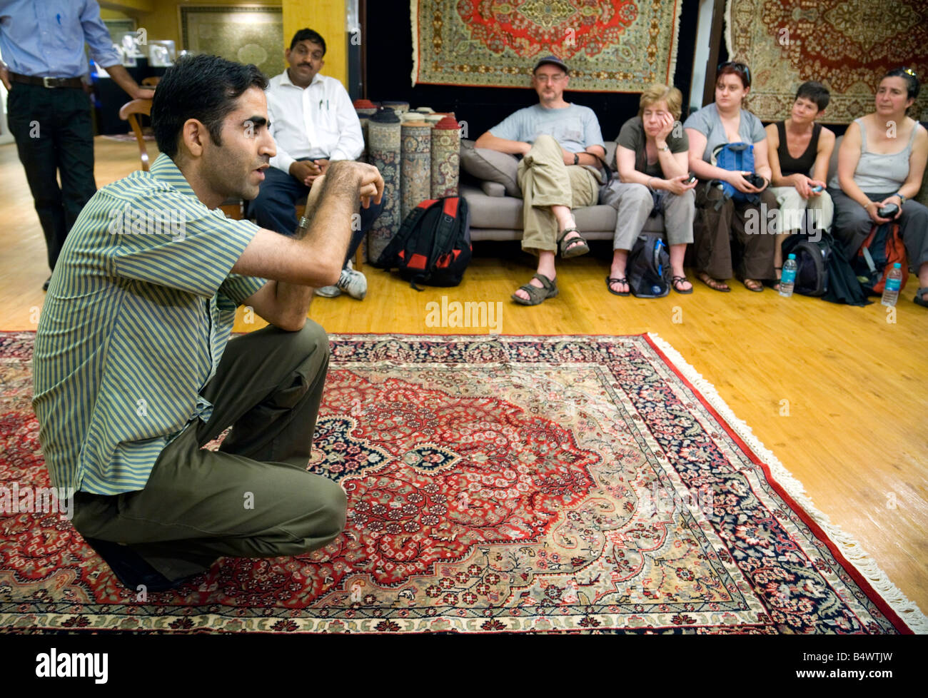 An Indian carpet expert explains to a group of Western tourists how the carpets are made; New Delhi, India Stock Photo