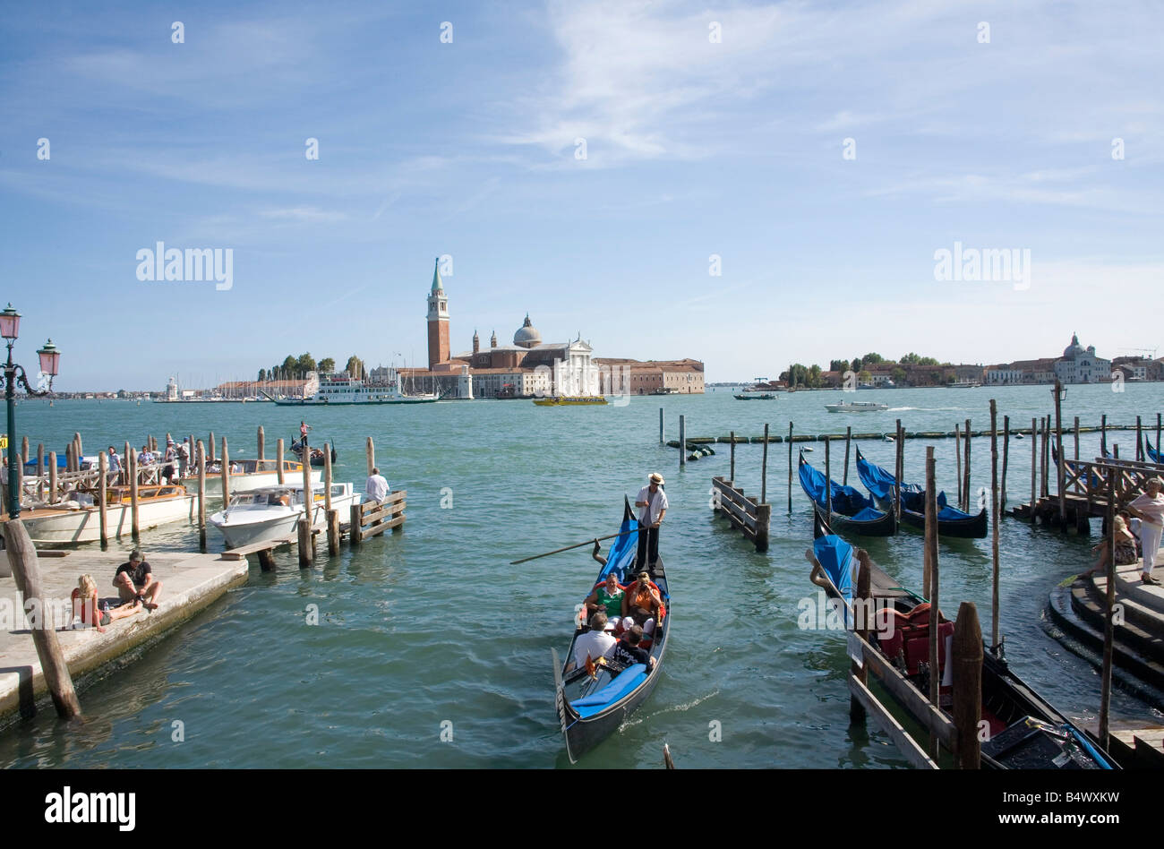 People taking a gondola Ride with the Basilica San Giorgio Maggiore across the Lagoon in the background Stock Photo