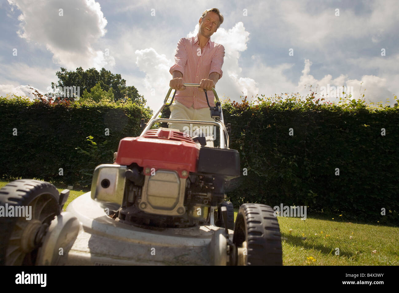 Man with push lawnmower, low angle Stock Photo