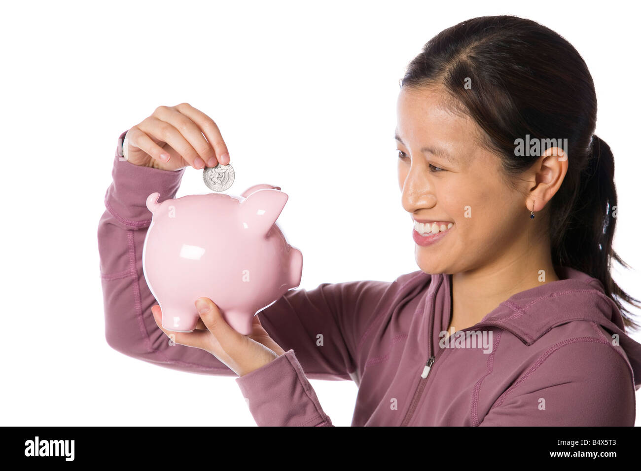 Young asian woman putting money into a piggy bank Stock Photo - Alamy