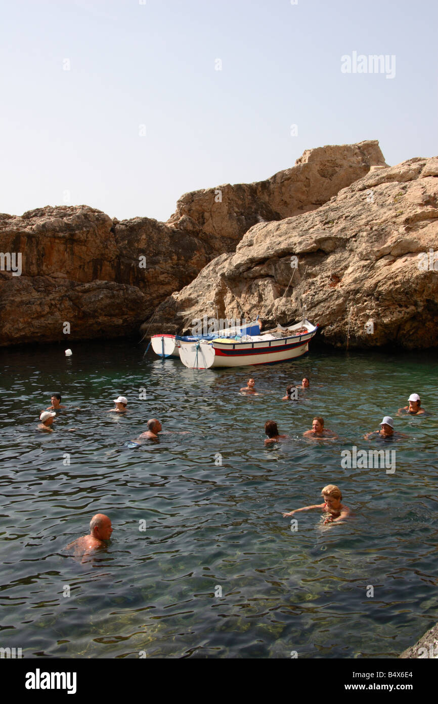 Local Maltese people swimming in a secluded bay at Ghar Lapsi in Malta