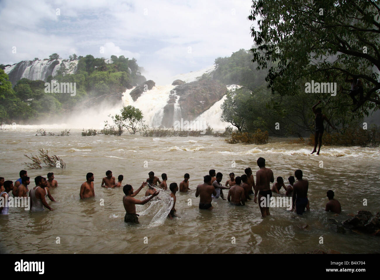 Men enjoy playing in the water under the swelled Gangachukki and Bharachukki waterfalls at Sivasudram in Karnataka, India. Stock Photo