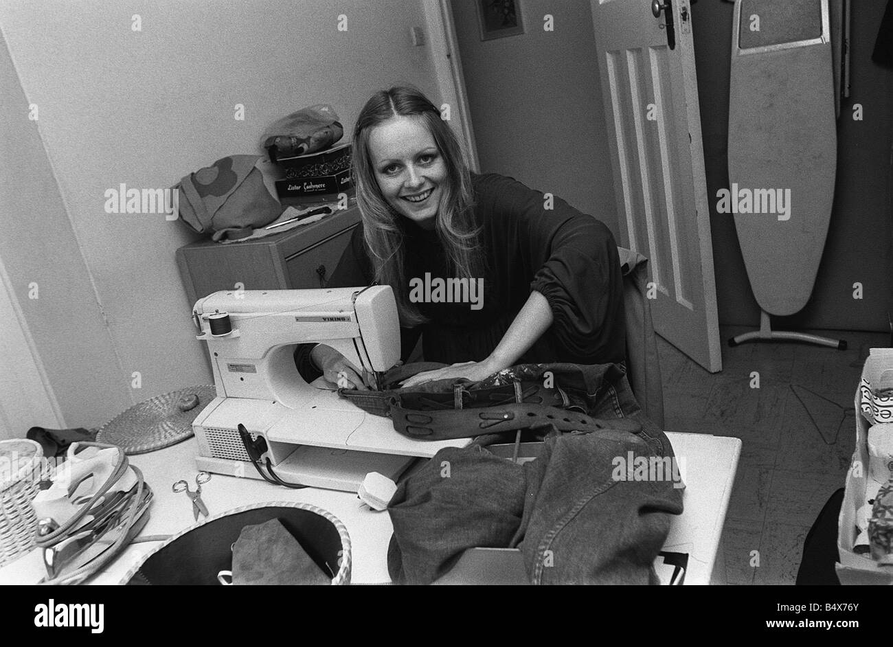 Model Twiggy at home using a sewing machine 1974 Stock Photo
