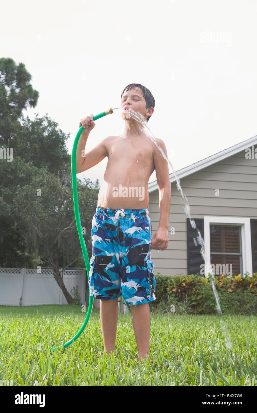 Boy drinking from garden hose in backyard Stock Photo Alamy