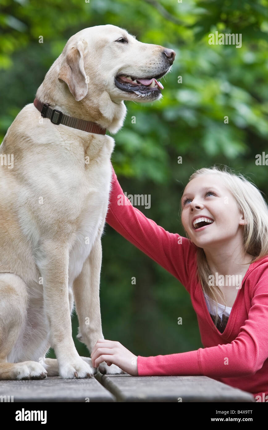 Girl petting dog sitting on picnic table Stock Photo Alamy