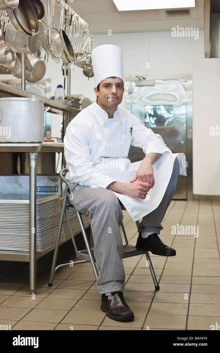 Chef sitting on stool in kitchen Stock Photo