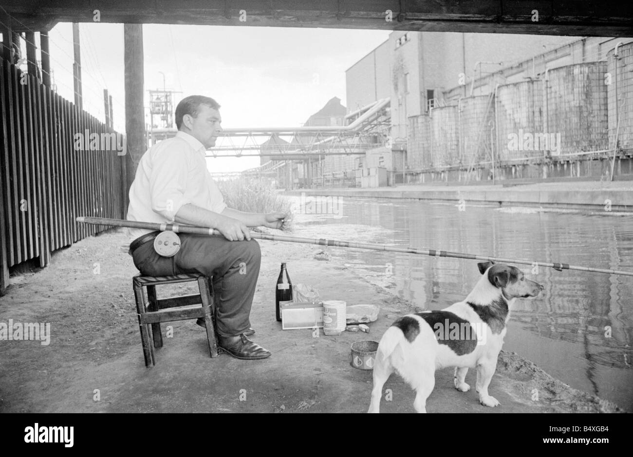 This man enjoys a smoke as he wait patiently for a 'bite' as he fishes in the Coventry Canal.;17th July 1967;Fishing;Angling;Dog;Water;Leisure/Pastimes/Hobbies;Core41;1960s Stock Photo