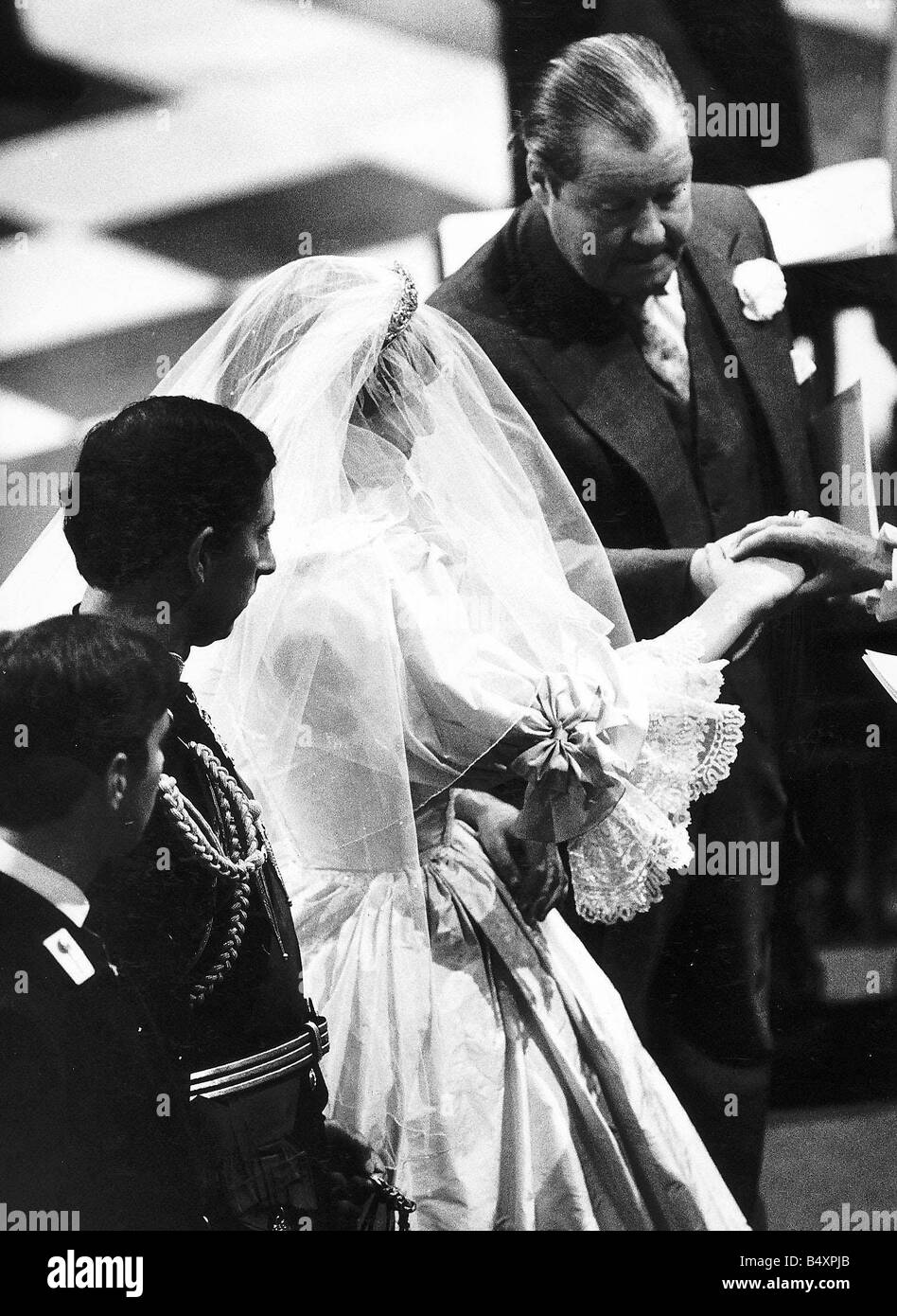 Prince Charles and Princess Diana exchange their wedding vows at St Pauls Cathedral in London The Earl Spencer passes his daughters hand over to prince Charles in the wedding ceremony watched over by Prince Andrew Stock Photo