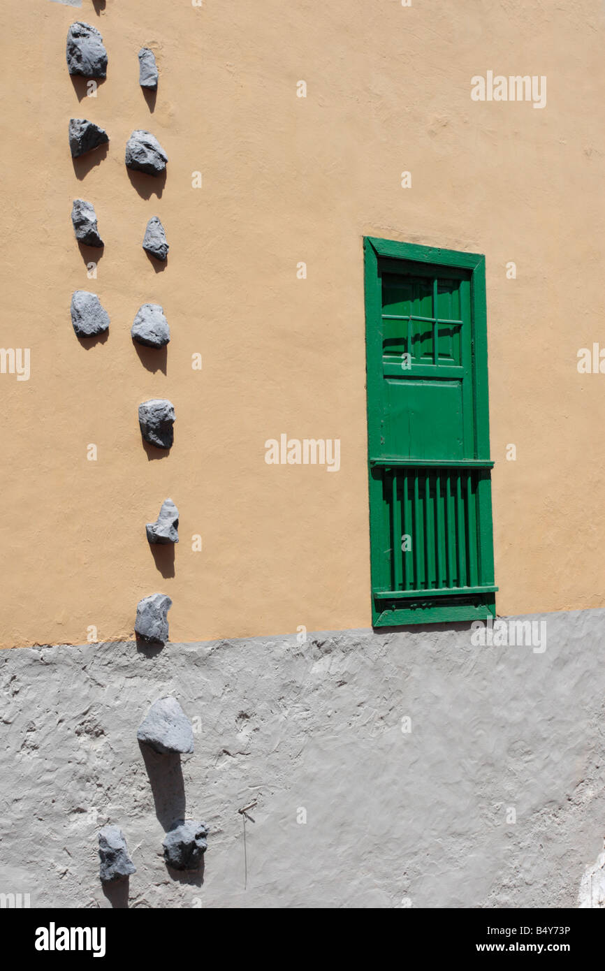 Wall with typical style of window and shutters and stones embedded on side of house in Guia de Isora, Tenerife Stock Photo