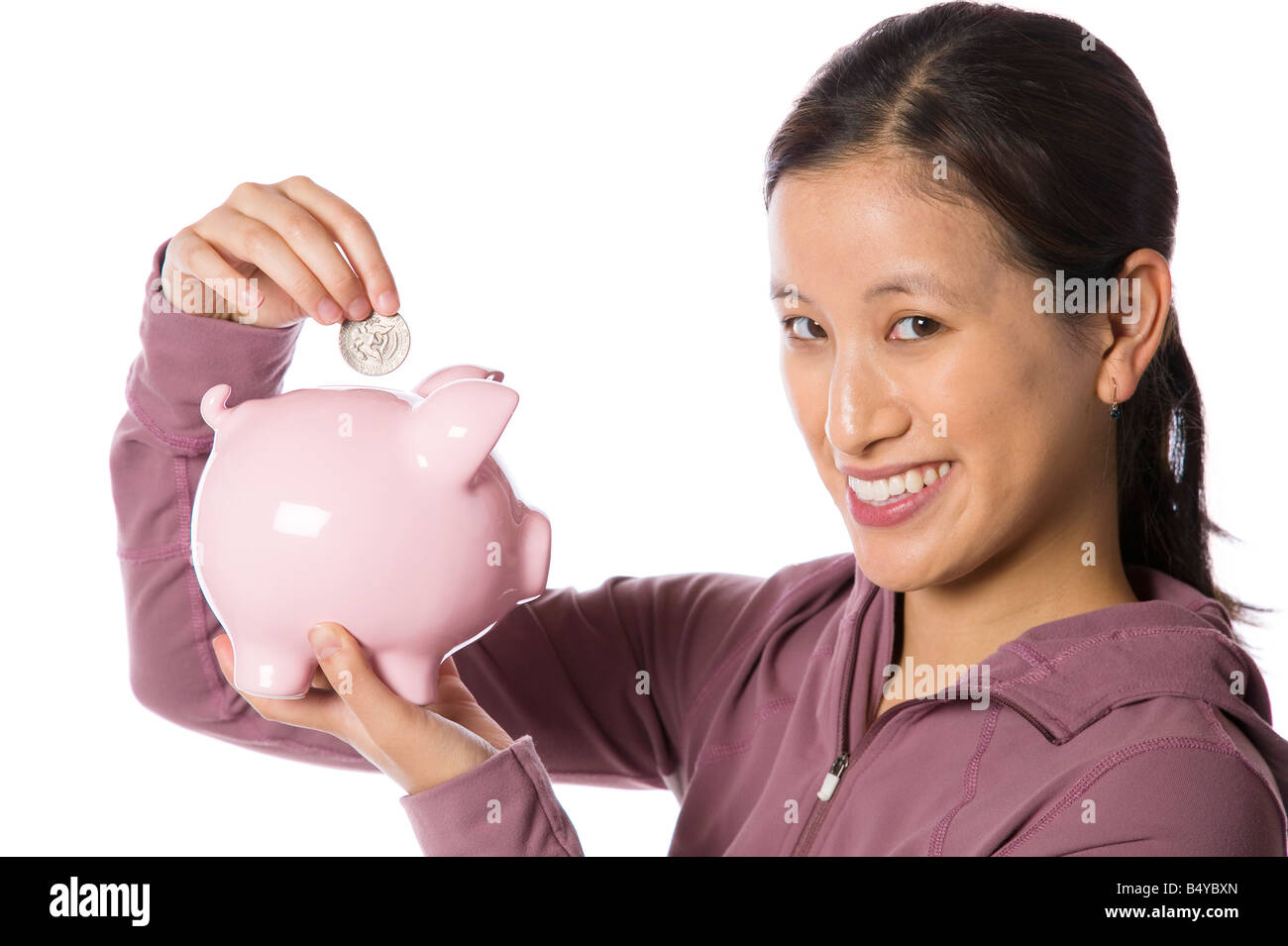Young asian woman putting money into a piggy bank Stock Photo - Alamy