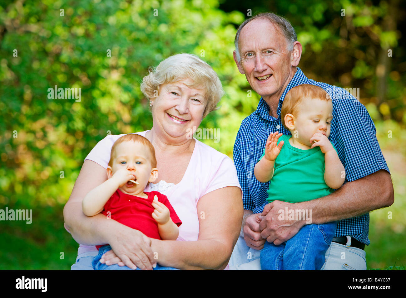 holding-redheaded-twin-grandsons-with-focus-on-happy-grandparents-stock